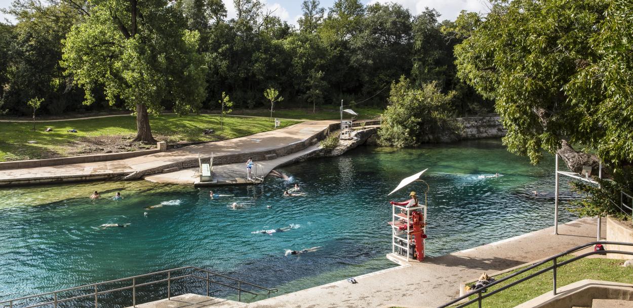 People swimming in Barton Springs Pool with lifeguard in stand