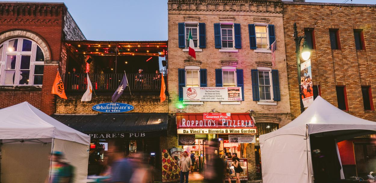 people walking down 6th Street in front of Roppolo's Pizzeria and Shakespeare's Pub in Austin Texas