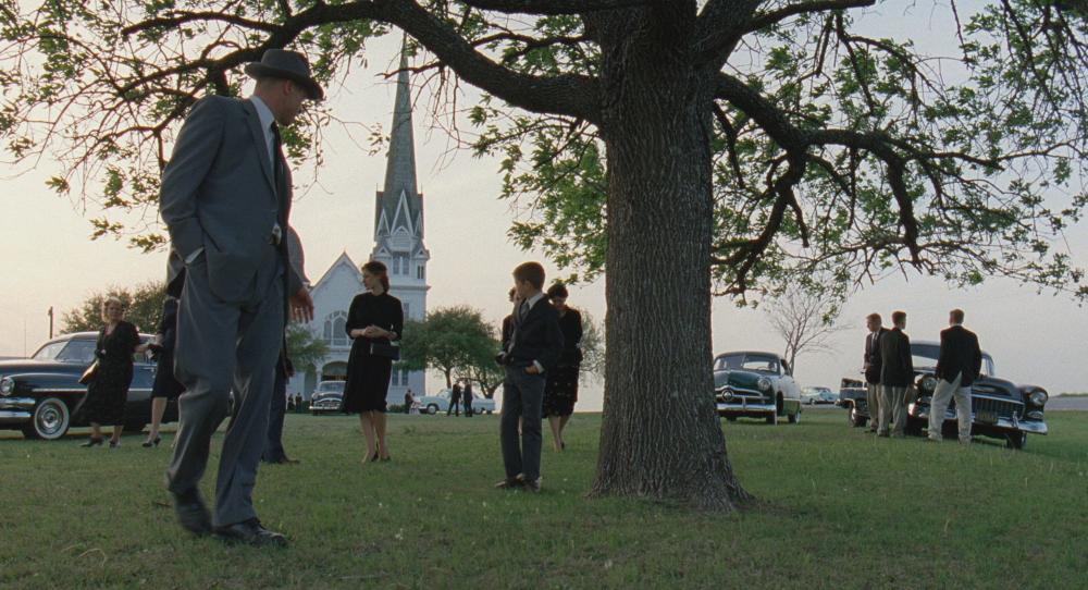 Tree of Life Screengrab, with a crowd of people outside a church, walking to their cars